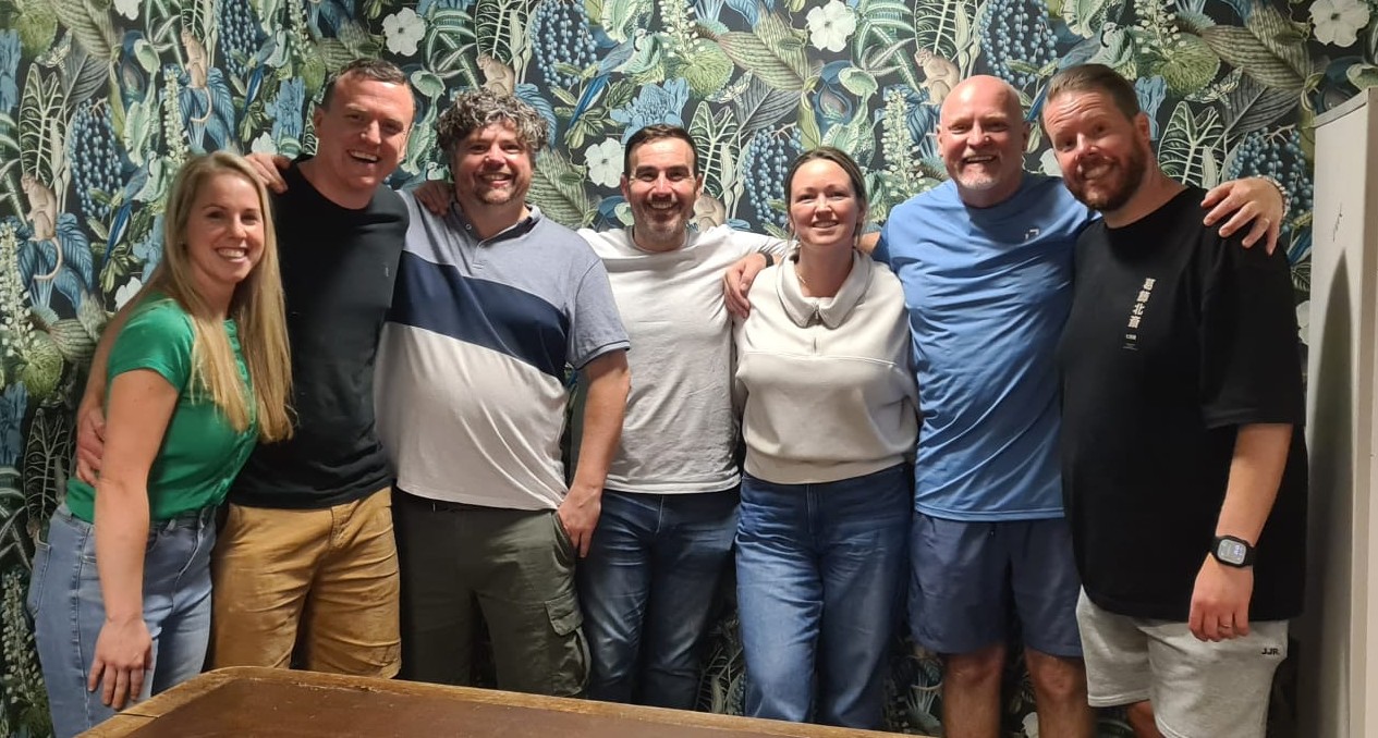 7 people in a line looking happy